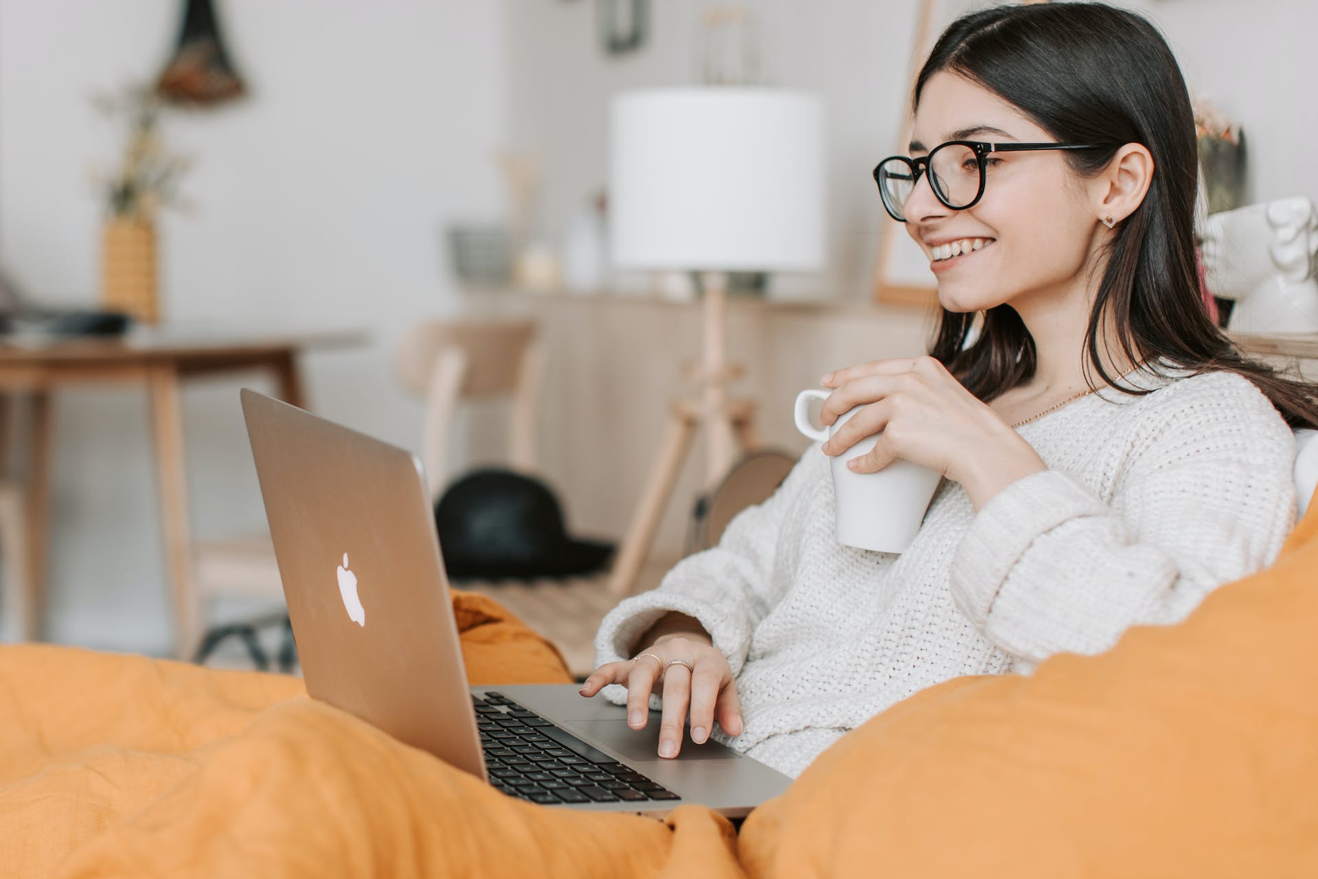 Woman sitting on couch with coffee and a laptop